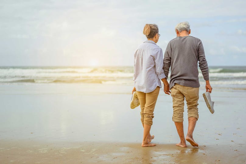 Altes Paar spaziert barfuss am Meer, Altersvorsorge