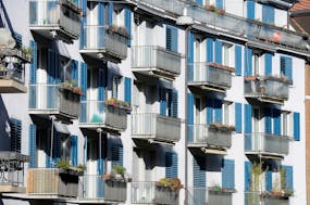 Wohnungen in Zürich, Häuserfassade mit Balkonen und blauen Fensterläden.