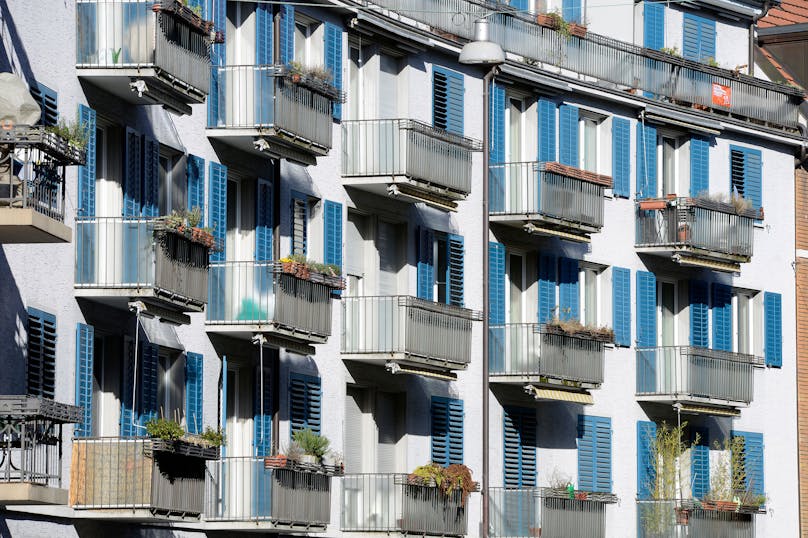 Wohnungen in Zürich, Häuserfassade mit Balkonen und blauen Fensterläden.