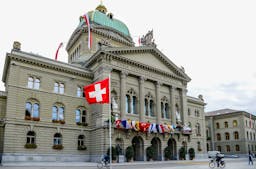 Bundeshaus in Bern, Schweiz, mit Landesfahne und Kantonsfahnen.